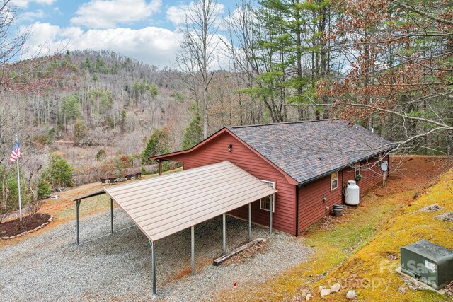 exterior space with gravel driveway and a wooded view