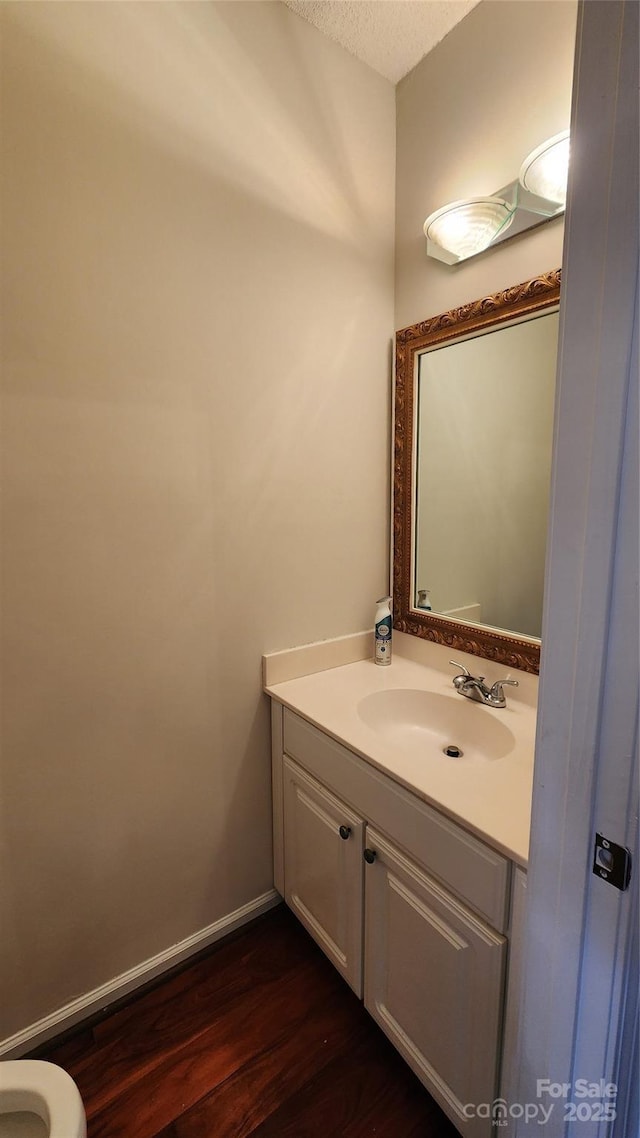 bathroom featuring a textured ceiling, wood finished floors, vanity, and baseboards