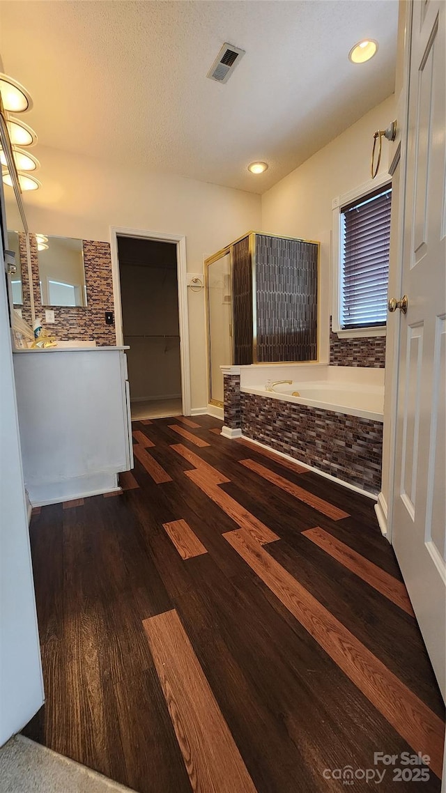 bathroom with wood finished floors, visible vents, vanity, a shower stall, and a bath