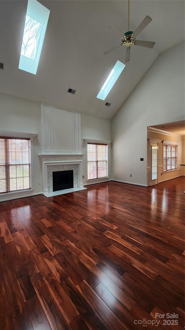 unfurnished living room with a wealth of natural light, a skylight, a fireplace, and visible vents