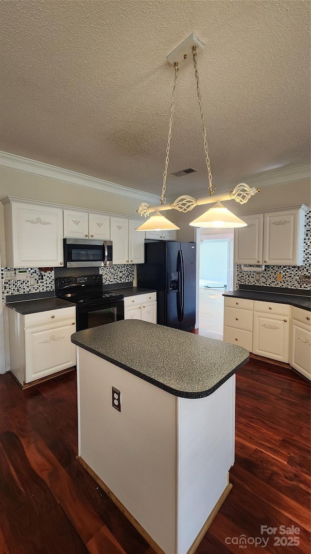 kitchen featuring dark countertops, black appliances, a kitchen island, and white cabinets