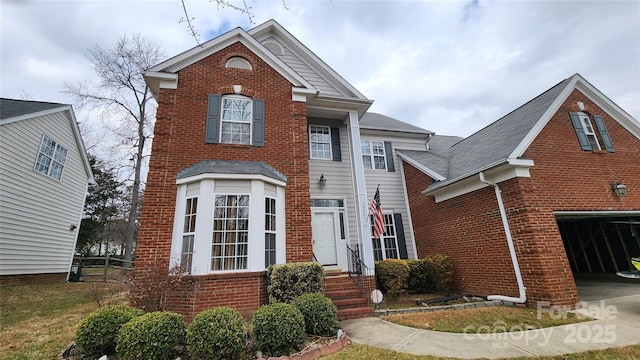 traditional home featuring driveway, brick siding, and an attached garage