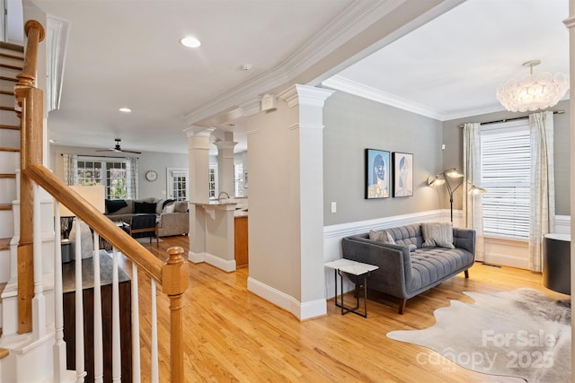 interior space with light wood finished floors, ornamental molding, stairway, and decorative columns