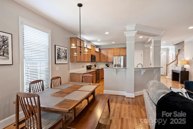 dining area featuring a wealth of natural light, decorative columns, and light wood finished floors