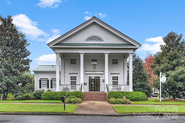 neoclassical / greek revival house with a porch, a front yard, a standing seam roof, and metal roof