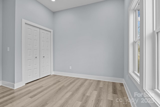 unfurnished bedroom with light wood-style floors, baseboards, and a closet