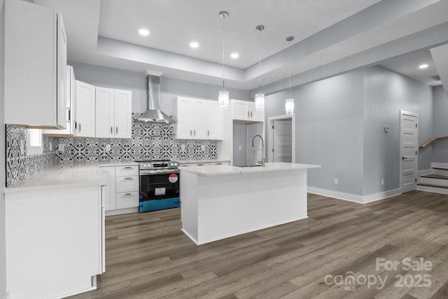 kitchen featuring stainless steel electric range oven, wall chimney exhaust hood, wood finished floors, and white cabinetry