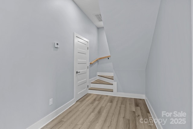 staircase with wood finished floors, visible vents, and baseboards