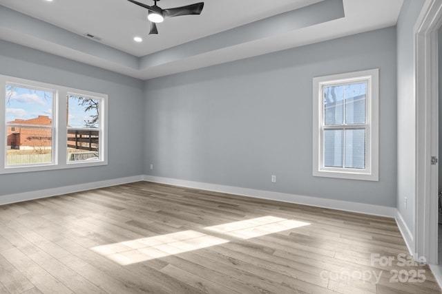 unfurnished bedroom featuring a raised ceiling, wood finished floors, and baseboards