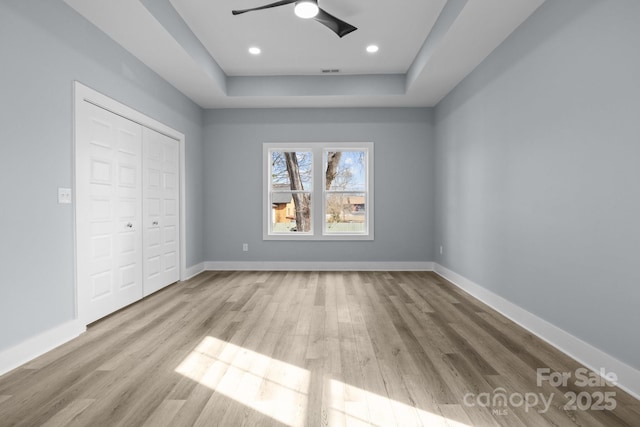 unfurnished bedroom with a closet, wood finished floors, visible vents, and baseboards