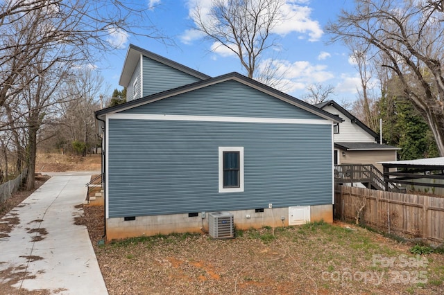 view of side of property with cooling unit, crawl space, fence, and concrete driveway