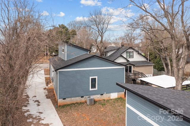 view of side of property with crawl space, a shingled roof, and cooling unit