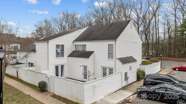 view of home's exterior with fence and roof with shingles