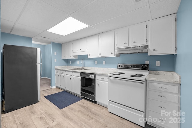 kitchen featuring under cabinet range hood, a sink, black dishwasher, white range with electric stovetop, and freestanding refrigerator