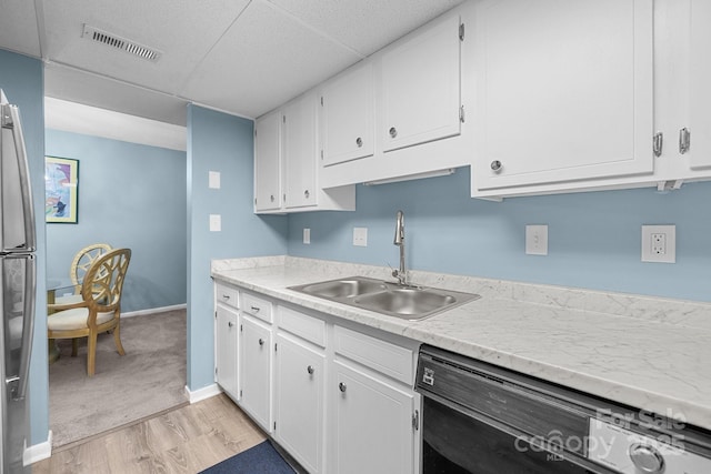 kitchen featuring dishwasher, visible vents, white cabinets, and a sink