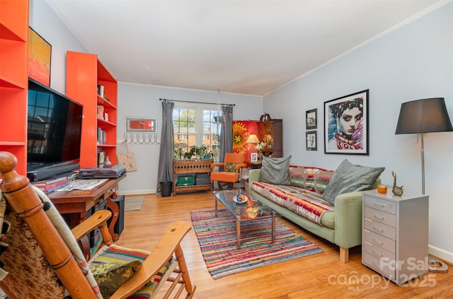 living area featuring ornamental molding, baseboards, and light wood finished floors