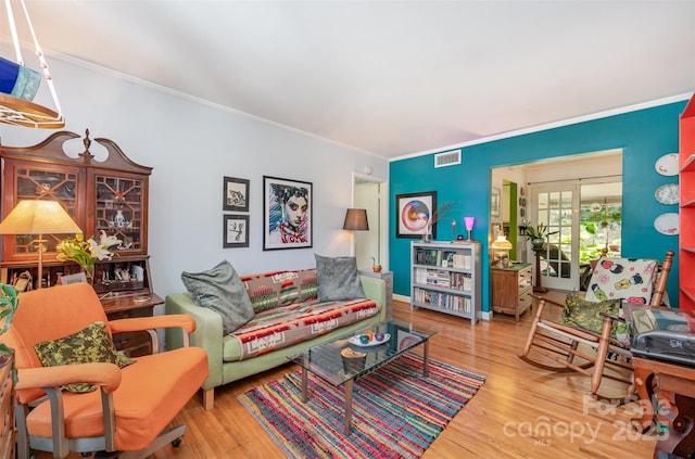 living room featuring visible vents, ornamental molding, and wood finished floors