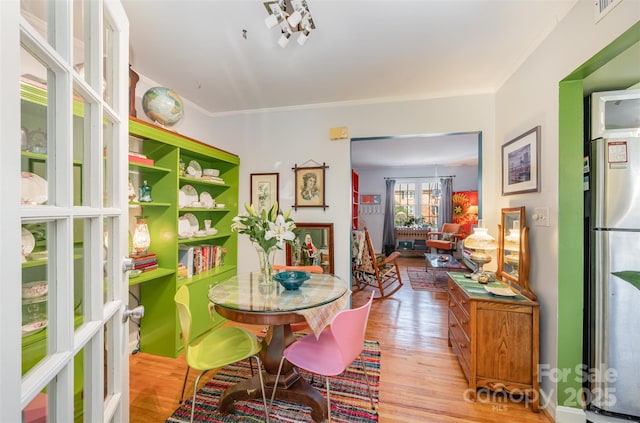 dining space with crown molding, visible vents, and wood finished floors