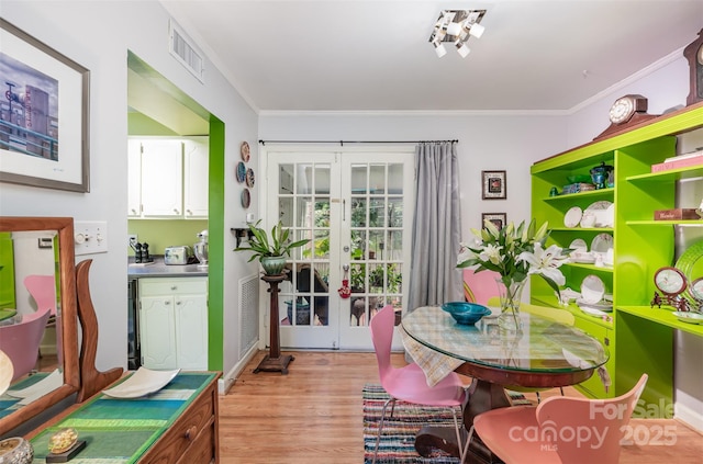 dining room featuring crown molding, french doors, visible vents, and light wood-style floors