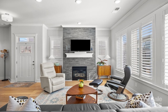 living room with visible vents, crown molding, baseboards, a fireplace, and wood finished floors