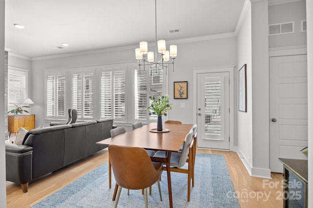 dining room featuring visible vents, light wood-style floors, and ornamental molding