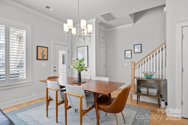 dining space with visible vents, an inviting chandelier, light wood-style flooring, stairs, and crown molding