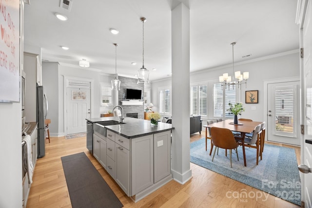 kitchen featuring light wood-style flooring, gray cabinets, freestanding refrigerator, and a sink