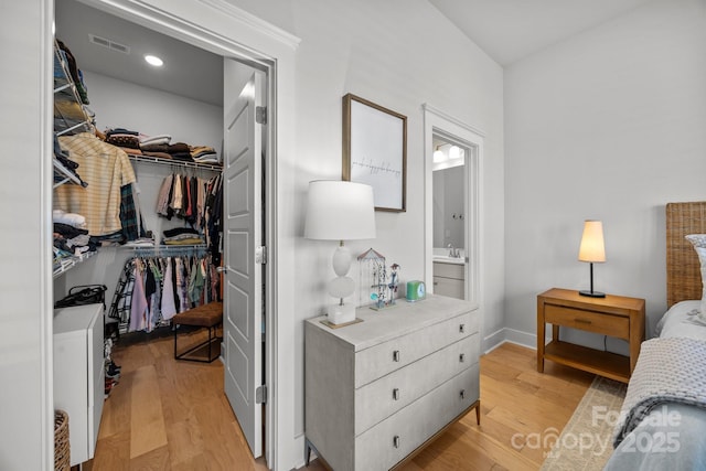 bedroom with a sink, a closet, visible vents, and light wood finished floors