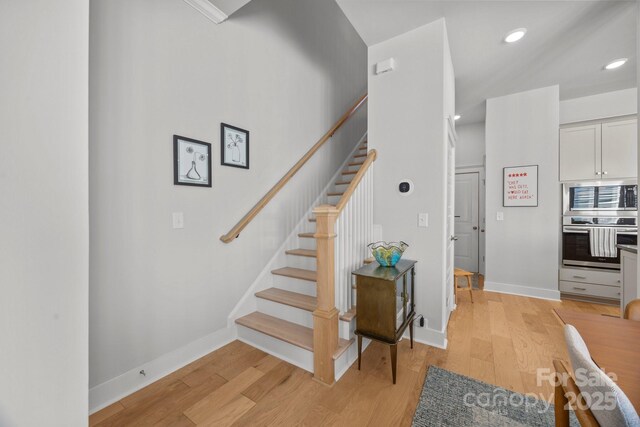 stairway featuring recessed lighting, baseboards, and wood finished floors