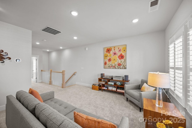 carpeted living area with recessed lighting, visible vents, and baseboards