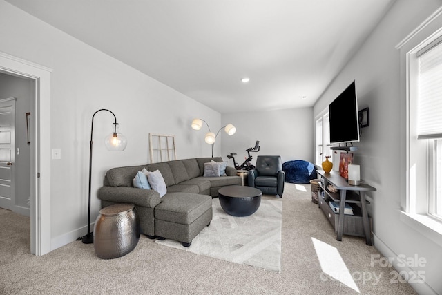 living room with a wealth of natural light, baseboards, and light carpet