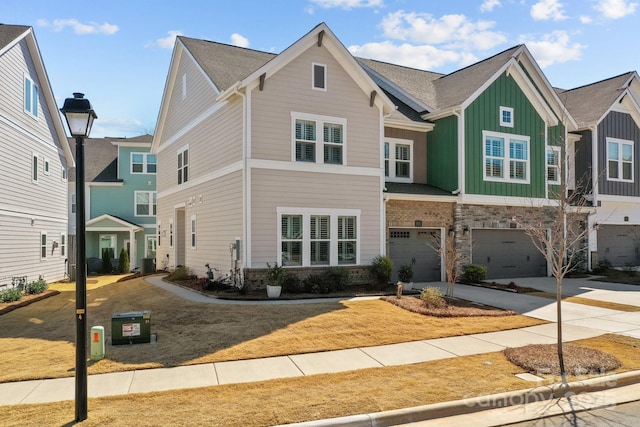 multi unit property with board and batten siding, central air condition unit, concrete driveway, a garage, and stone siding