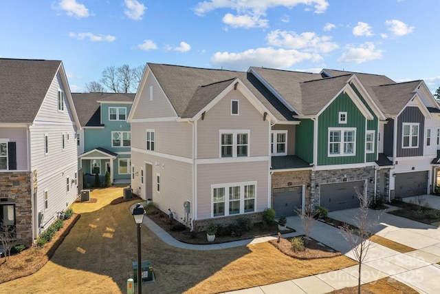 townhome / multi-family property with stone siding, an attached garage, board and batten siding, and driveway