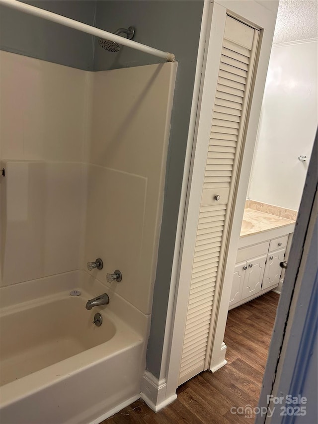 bathroom featuring shower / tub combination, wood finished floors, a textured ceiling, vanity, and a closet