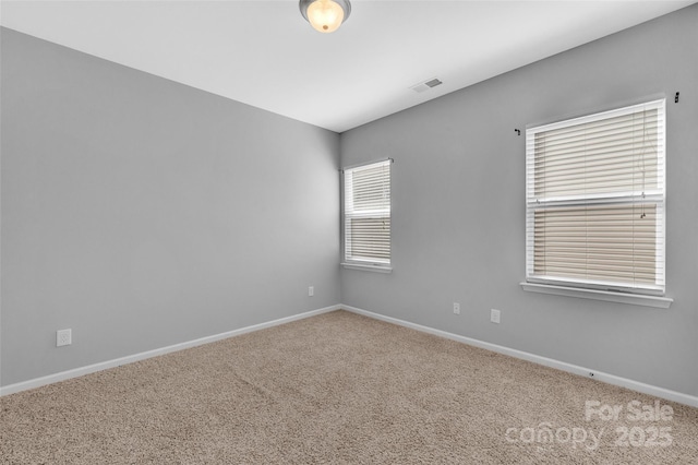 unfurnished room featuring baseboards, visible vents, and carpet flooring