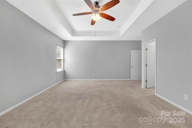 unfurnished room with light carpet, ceiling fan, baseboards, and a raised ceiling