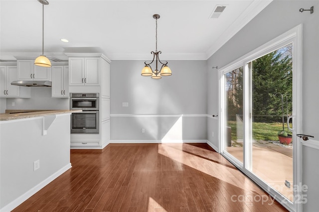 kitchen featuring dark wood-type flooring, pendant lighting, under cabinet range hood, and baseboards