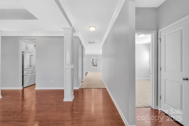 corridor featuring visible vents, dark wood-style floors, decorative columns, and baseboards