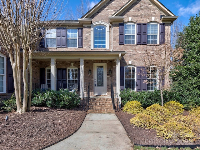 view of front of home featuring covered porch and brick siding