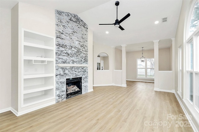 unfurnished living room featuring visible vents, built in features, decorative columns, a tile fireplace, and a ceiling fan