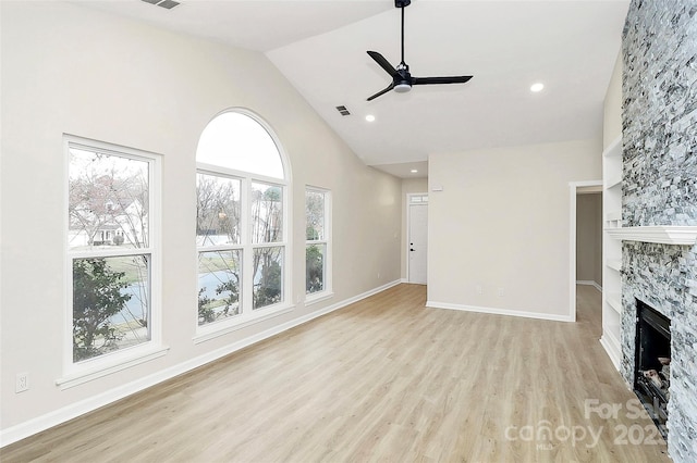 unfurnished living room with light wood-type flooring, high vaulted ceiling, a ceiling fan, a fireplace, and baseboards