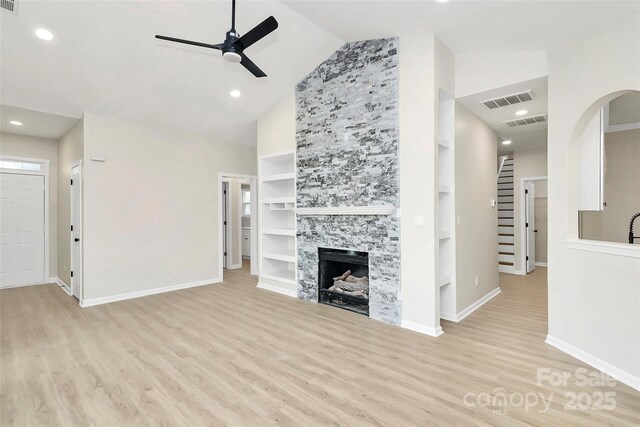 unfurnished living room featuring visible vents, a ceiling fan, wood finished floors, a fireplace, and stairs