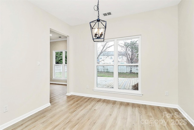 unfurnished dining area featuring a chandelier, light wood-style flooring, and baseboards