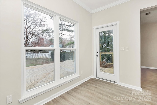 entryway with crown molding, baseboards, light wood-type flooring, and visible vents