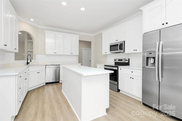 kitchen featuring light wood-style flooring, a sink, a center island, appliances with stainless steel finishes, and crown molding