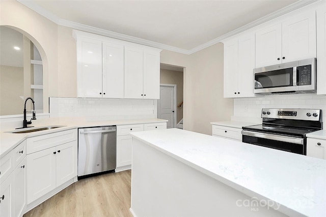 kitchen featuring a sink, crown molding, light countertops, and stainless steel appliances