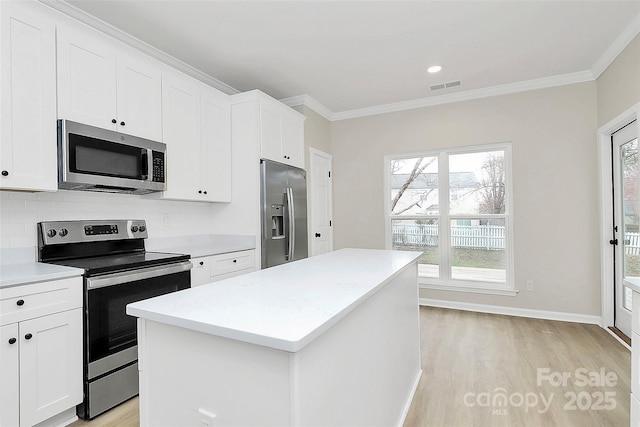 kitchen with visible vents, a kitchen island, crown molding, decorative backsplash, and stainless steel appliances