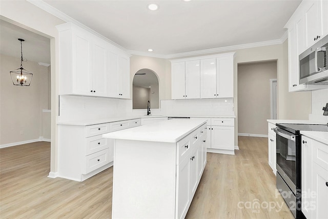 kitchen with a sink, stainless steel appliances, arched walkways, crown molding, and light countertops