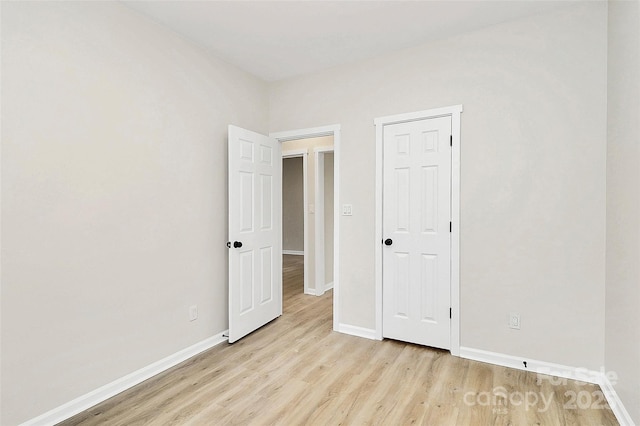 spare room with baseboards and light wood-style floors