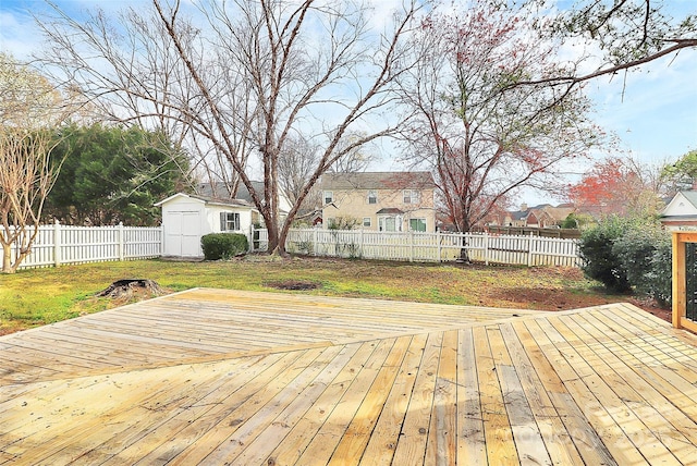 wooden terrace featuring a shed, a residential view, a yard, a fenced backyard, and an outbuilding